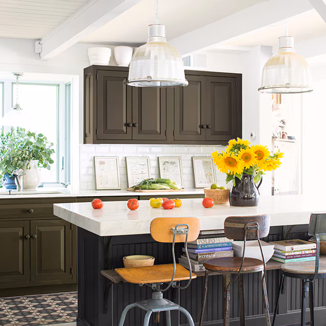 Kitchen with deep brown painted cabinets, a black beadboard island, and white marble counters