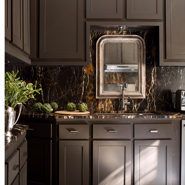 Smooth, even painted cabinet doors in a deep brown finish beside a dark marble backsplash