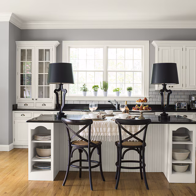 Bright kitchen with white painted cabinets, a black-topped island, and soft gray walls